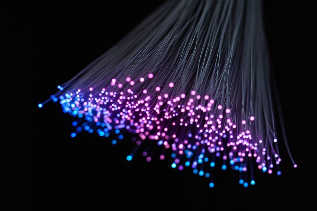 Glowing fiber optic cable ends in violet and teal light
